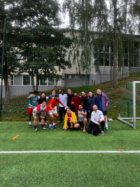 Group photo of players giving thumbs up by the goal on an outdoor turf pitch